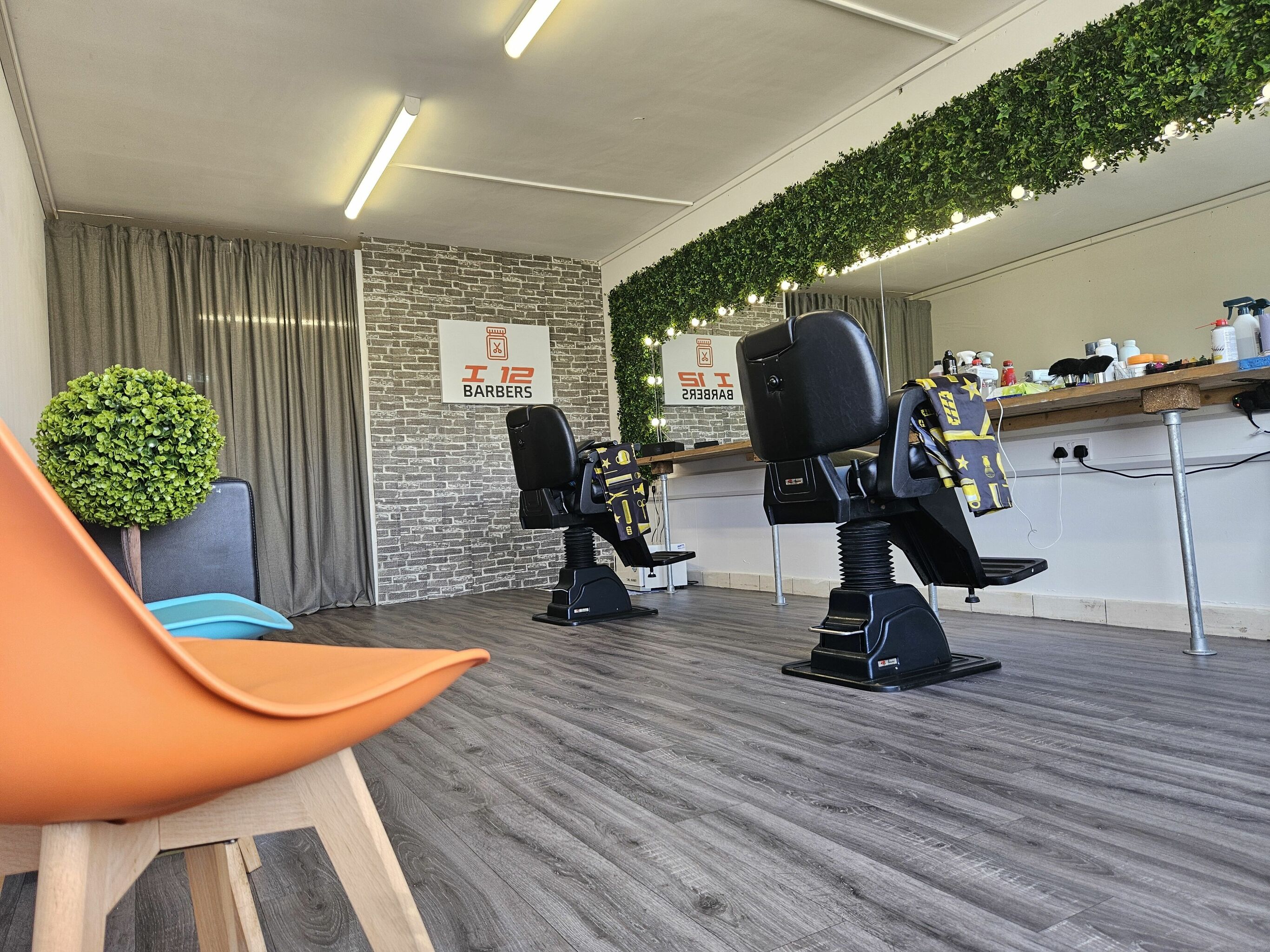 Inside i12 Barbers: two barber chairs, the leaf wall with its lights and the i12 sign